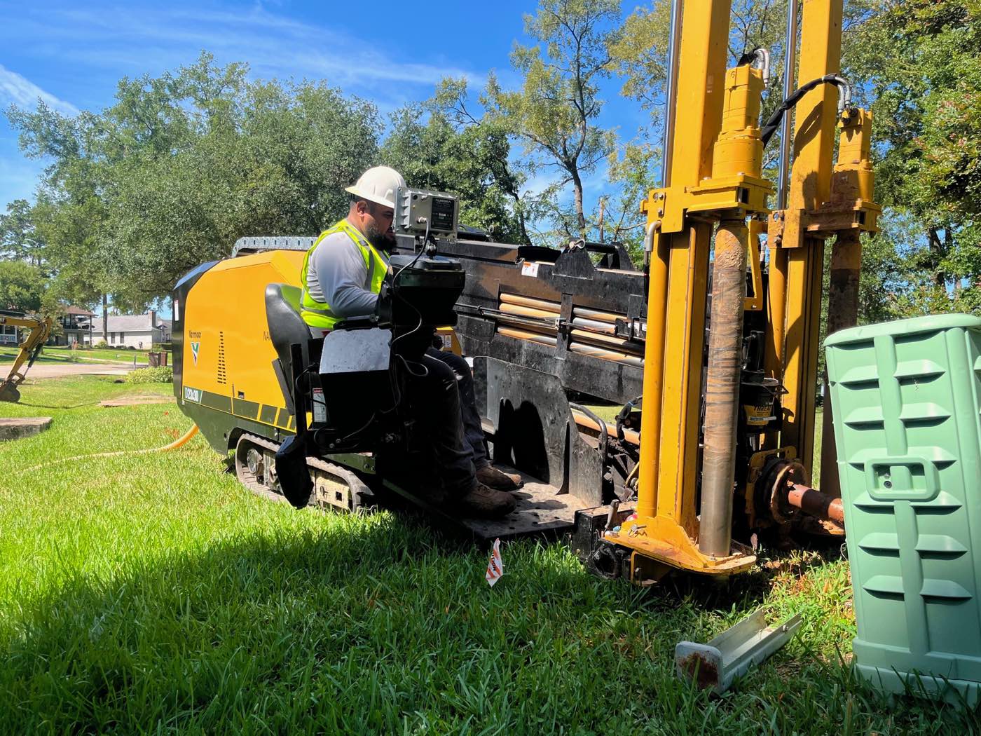A One World Communications operator running a directional drill rig, boring conduit beside a residential street