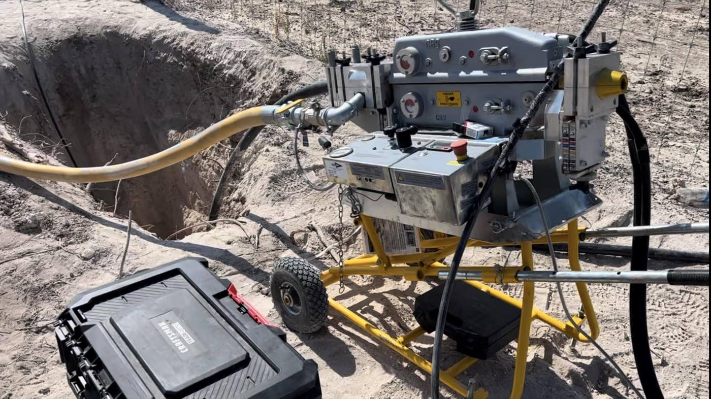 A cable blowing machine feeding fiber into conduit at an open trench on a One World Communications job