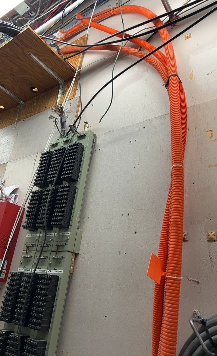 Inside plant work on a One World Communications job, terminal blocks landed on the backboard with orange innerduct risers running up the wall