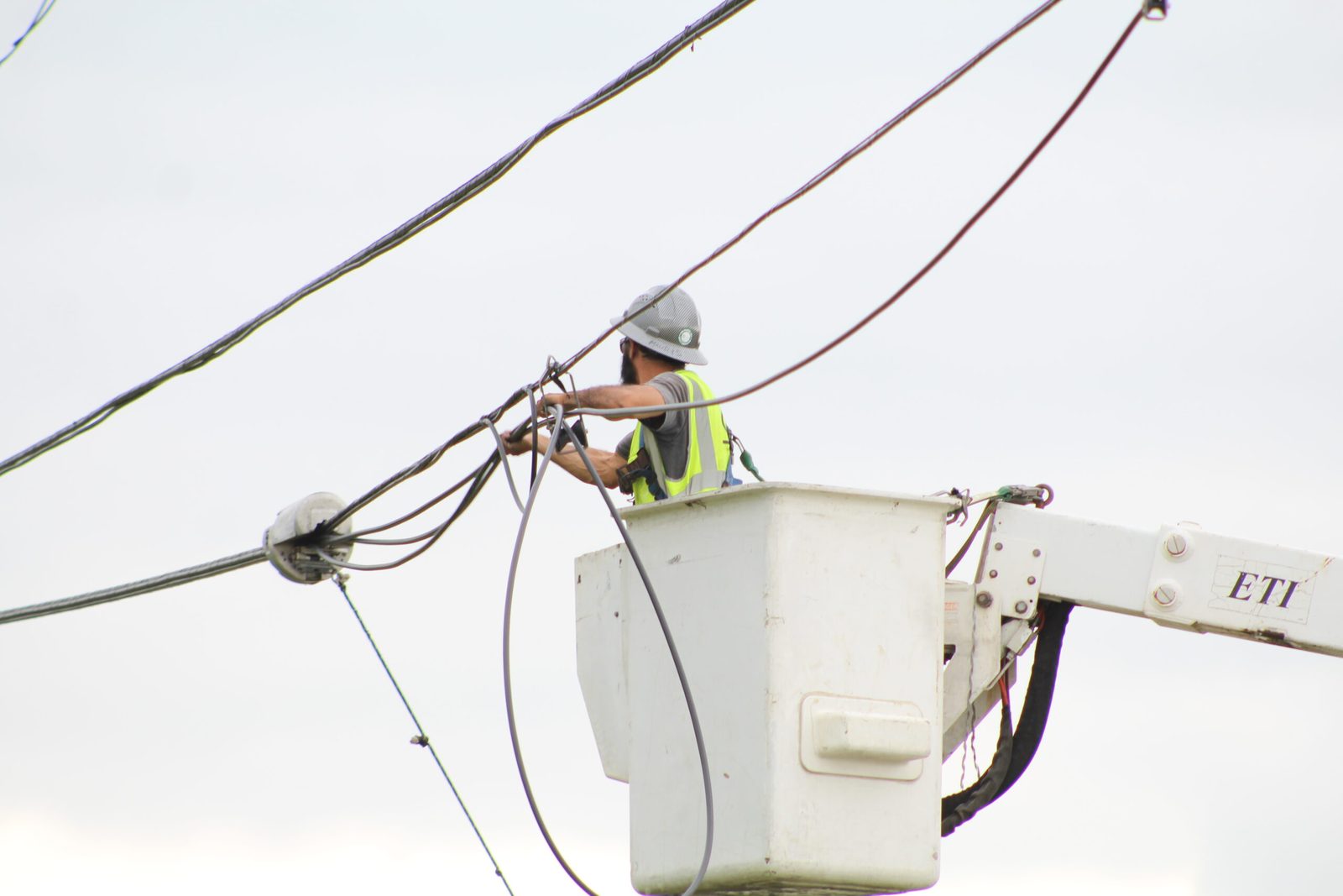A One World Communications technician working aerial communications lines at height