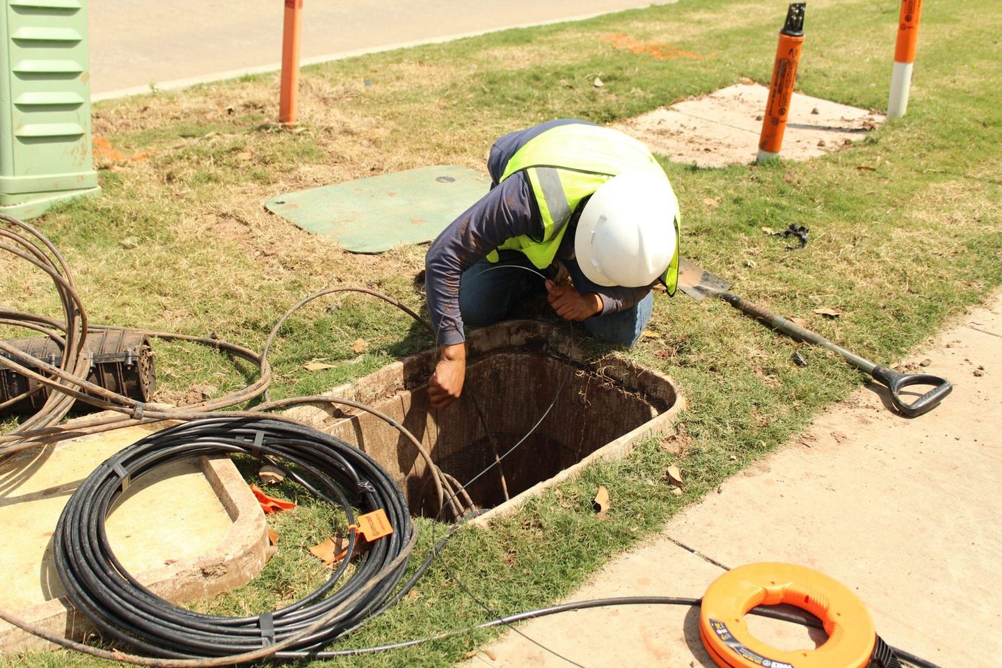 A One World Communications technician working at an open handhole